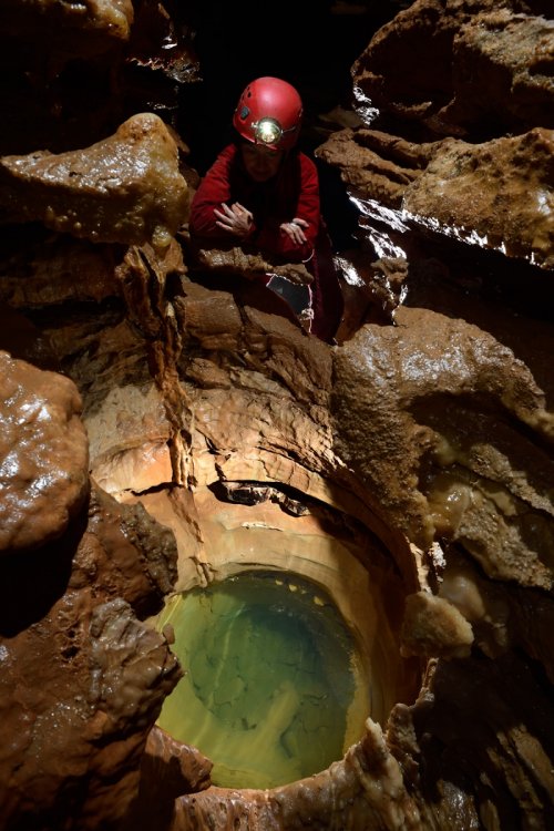 La Combe aux Prêtres - Réseau nord : spéléo regardant une marmite d'eau verte(SP-19-1978 )